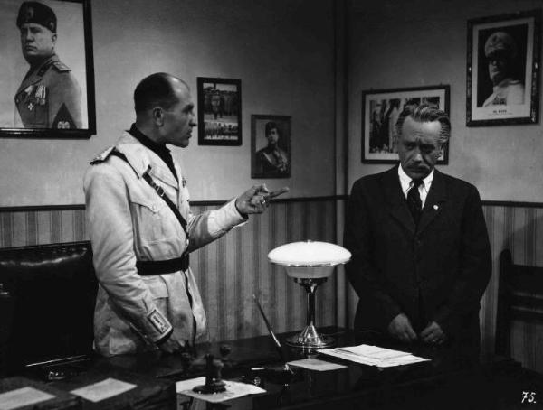 Scena del film "Anni difficili" - Regia Luigi Zampa - 1948 - L'attore Umberto Spadaro e un attore non identificato in una camera tappezzata di fotografie di Benito Mussolini