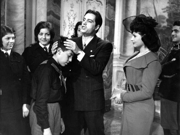 Scena del film "Anni ruggenti" - Regia Luigi Zampa - 1962 - Gli attori Nino Manfredi, con le mani in testa a un bambino in camicia nera fascista, Angela Luce