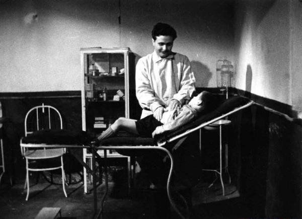 Set del film documentario "Anopheles" - Regia Giampiero Pucci - 1950 - Un medico visita un bambino steso sul lettino