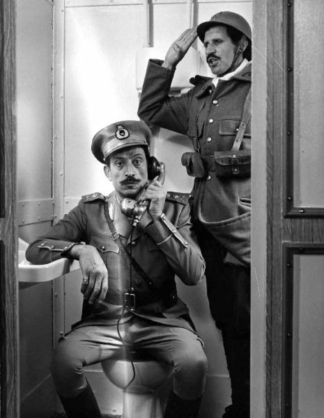 Scena del film "Armiamoci e partite" - Regia Nando Cicero - 1971 - Gli attori Ciccio Ingrassia e Philippe Clay al telefono in divisa militare seduto sul gabinetto