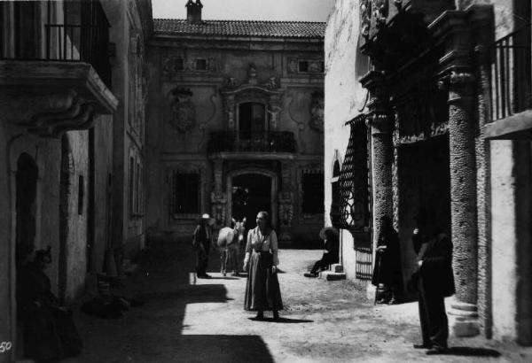 Scena del film "La bella addormentata" - Regia Luigi Chiarini - 1942 - L'attrice Luisa Ferida per le strade del paese tra attori non identificati e un asino