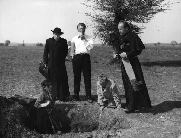 Scena del film "Il bidone" - Federico Fellini - 1955 - Gli attori Richard Basehart, Franco Fabrizi e Broderick Crawford vestito da prete e due attrici non identificate che scavano una buca
