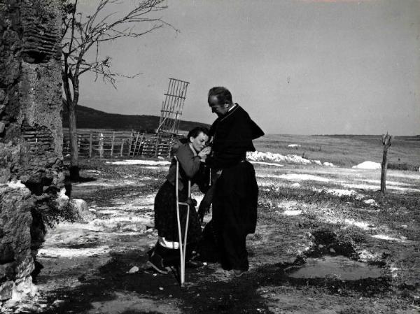 Scena del film "Il bidone" - Federico Fellini - 1955 - L'attore Richard Basehart vestito da prete e una donna inginocchiata davanti a lui