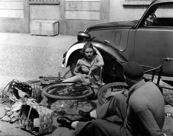 Scena del film "Il campione" - Carlo Borghesio - 1943 - L'attrice Fiorella Betti a terra accanto a una bicicletta e un'automobile