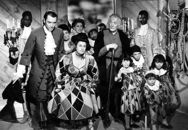 Scena del film "La carrozza d'oro" - Regia Jean Renoir - 1952 - Gli attori Paul Campbell, Anna Magnani, il bambino Dante in costume da arlecchino e attori non identificati