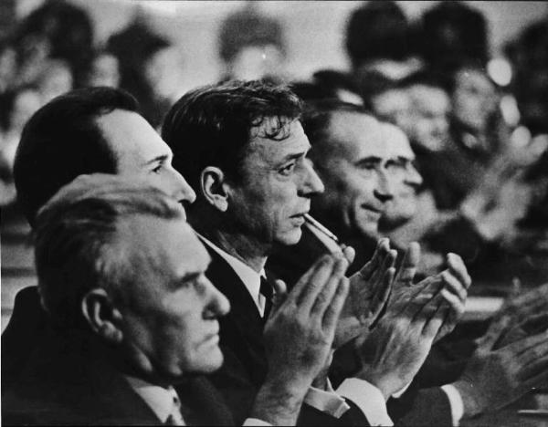 Scena del film "La Confessione" - Regia Constantin Costa-Gavras - 1970 - L'attore Yves Montand, con una sigaretta in bocca, applaude insieme ad altri attori non identificati