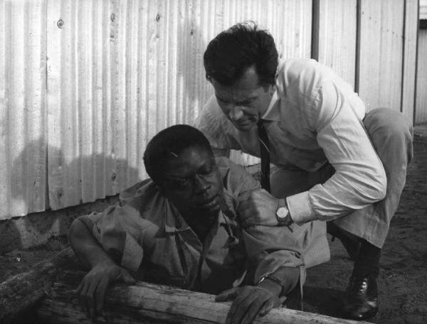 Scena del film "Congo vivo" - Regia Giuseppe Bennati - 1961- L'attore Bachir Touré, ferito, viene aiutato dall'attore Gabriele Ferzetti accovacciato alle sue spalle