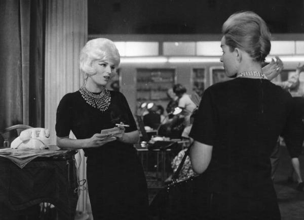 Set del film "Crimen" - Regia Mario Camerini- 1960 - L'attrice Silvana Mangano fuma e chiacchiera con un'attrice non identificata di spalle.

.