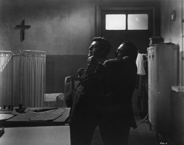 Set del film "Cronaca familiare" - Regia Valerio Zurlini 1962 - L'attore Marcello Mastroianni trattenuto per le spalle da attore non identificato in una stanza d'ospedale.