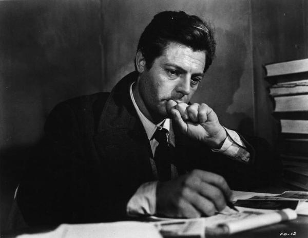 Set del film "Cronaca familiare" - Regia Valerio Zurlini 1962 - L'attore Marcello Mastroianni seduto alla scrivania in posa pensosa.