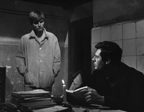 Set del film "Cronaca familiare" - Regia Valerio Zurlini 1962 - L'attore Jacques Perrin in pigiama in piedi accanto all'attore Marcello Mastroianni seduto alla scrivania.