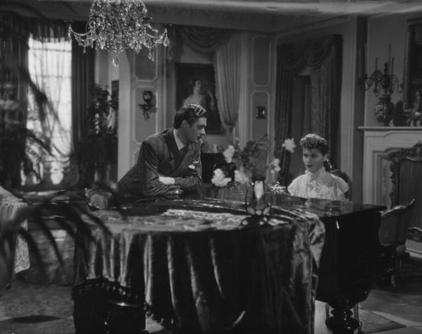 Fotografia del film "La danza del fuoco" - Regia Giorgio Simonelli 1942 - L'attore Carlo Minello ascolta l'attrice Luisella Beghi mentre suona il pianoforte.