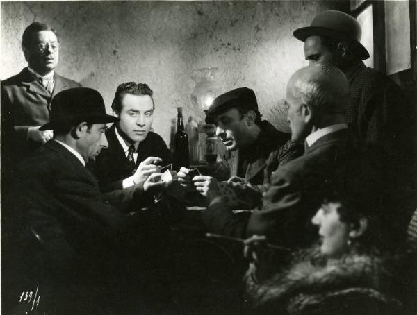 Scena del film "Il delitto di Giovanni Episcopo" - Regia Alberto Lattuada, 1947 - Roldano Lupi gioca a carte con altri uomini. Aldo Fabrizi, in piedi alle sue spalle, guarda la scena.