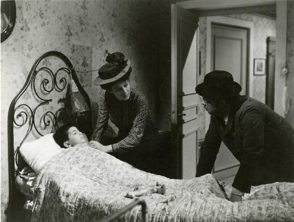 Scena del film "Il delitto di Giovanni Episcopo" - Regia Alberto Lattuada, 1947 - Yvonne Sanson e Aldo Fabrizi chinati sul letto del figlio, si guardano. Lei alla testa, lui ai piedi, appoggiano le mani sulle coperte.