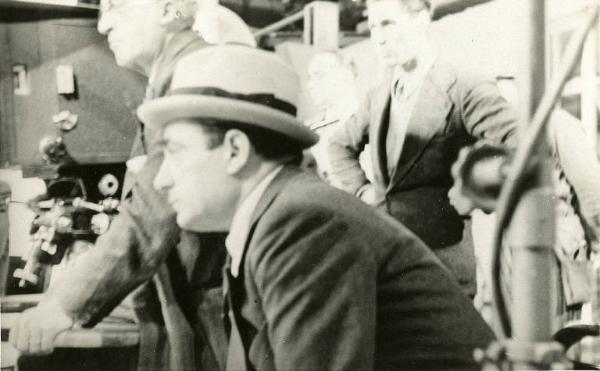 Sul set del film "Il destino in tasca" - Regia Gennaro Righelli, 1938 - Uomo seduto non identificato. Sullo sfondo cineprese e operatori.