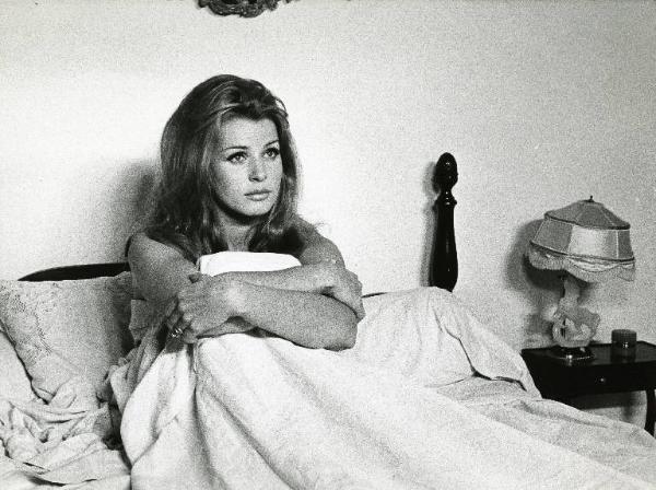 Scena del film "Diabolicamente tua" - Regia Julien Duvivier, 1968 - Senta Berger nel letto, seduta, tiene le gambe raggomitolate tra le sue braccia, con lo sguardo fisso.