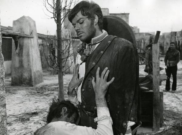 Scena del film "10.000 dollari per un massacro" - Regia Romolo Girolami, 1967 - Claudio Camaso guarda con disprezzo Mirko Valentin che, inginocchiato davanti a lui, gli appoggia entrambe le mani sul petto e piange.