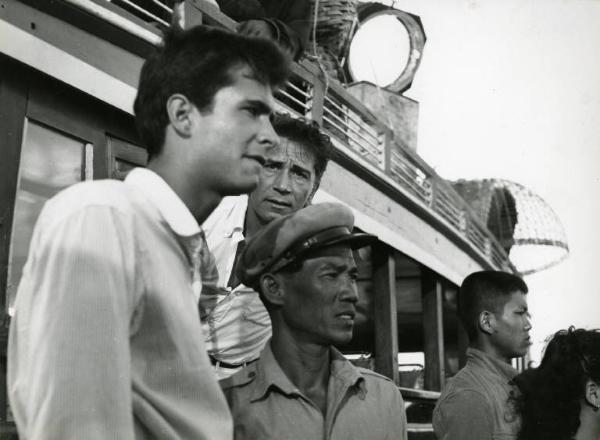 Scena del film "La diga sul Pacifico" - Regia René Clément, 1957 - Mezza figura di profilo di Anthony Perkins accanto a un autobus dal quale si sporge Richard Conte. Nella foto, sono presenti attori non identificati di origine asiatica.