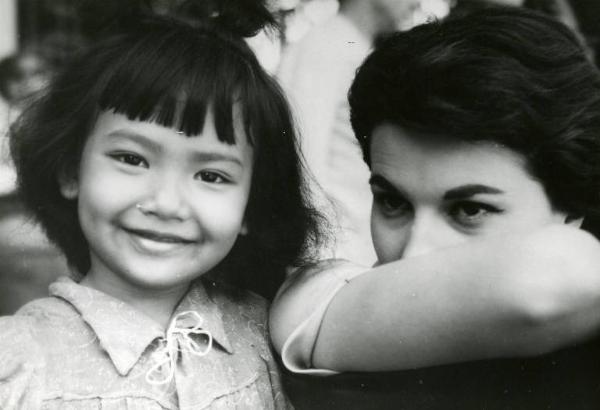 Scena del film "La diga sul Pacifico" - Regia René Clément, 1957 - Primo piano di Silvana Mangano, col braccio destro davanti alla bocca. Accanto a lei una bambina non identificata sorride.