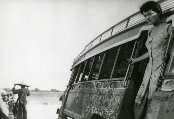 Scena del film "La diga sul Pacifico" - Regia René Clément, 1957 - Piano americano di Silvana Mangano in piedi su un bus. L'attrice e il mezzo sono sporchi di fango. Sullo sfondo un uomo di spalle non identificato.