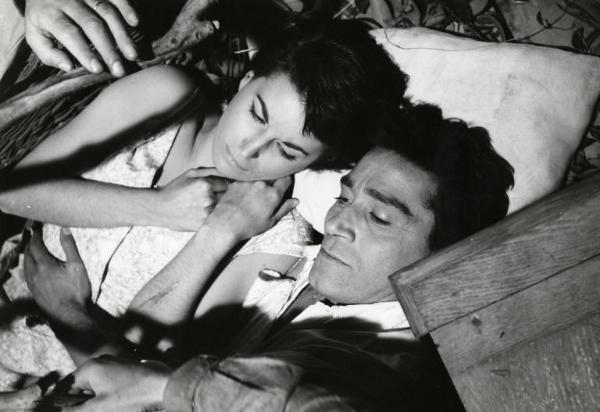 Scena del film "La diga sul Pacifico" - Regia René Clément, 1957 - Silvana Mangano e Richard Conte sdraiati supini con la testa appoggiata a un cuscino. Lui le cinge la vita con un braccio, lei ha entrambe le mani sul collo.