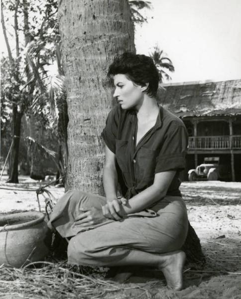 Scena del film "La diga sul Pacifico" - Regia René Clément, 1957 - Figura intera di Silvana Mangano accovacciata ai piedi di un albero, davanti a lei un vaso.