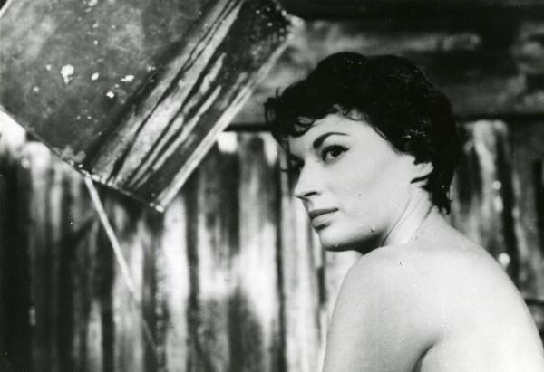 Scena del film "La diga sul Pacifico" - Regia René Clément, 1957 - Primo piano di profilo di Silvana Mangano con le spalle nude. In alto a sinistra, un secchio doccia vuoto.