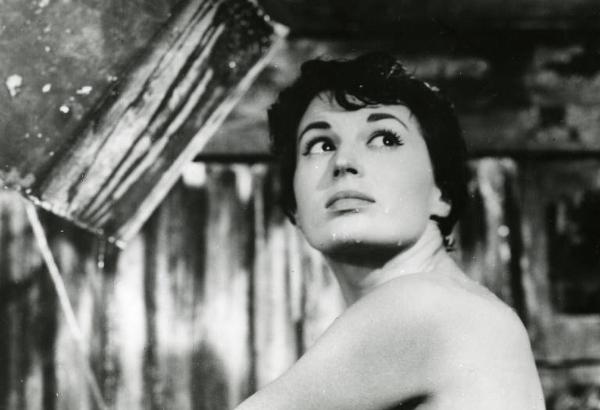 Scena del film "La diga sul Pacifico" - Regia René Clément, 1957 - Primo piano frontale di Silvana Mangano con le spalle nude e gli occhi rivolti in alto a destra. In alto a sinistra, un secchio doccia vuoto.