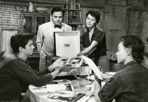 Scena del film "La diga sul Pacifico" - Regia René Clément, 1957 - Intorno a un tavolo Nehemiah Persoff e Silvana Mangano, in piedi, con Anthony Perkins e Jo Van Fleet, seduti, guardano e si scambiano foto e documenti.