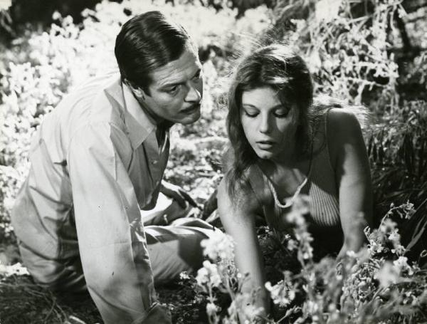 Scena del film "Divorzio all'italiana" - Regia Pietro Germi, 1961 - Marcello Mastroianni e Stefania Sandrelli ripresi in primo piano, carponi: lui la guarda fissamente mentre lei guarda i fiori di campo.