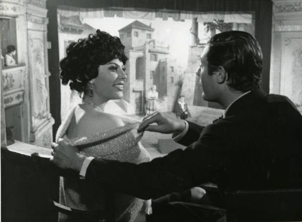 Scena del film "Divorzio all'italiana" - Regia Pietro Germi, 1961 - Mezza figura di profilo di Marcello Mastroianni e Daniela Rocca seduti in un palco di teatro. Lei lo guarda sorridendo mentre lui le copre la spalla con il vestito.