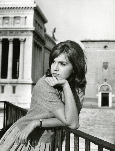 Scena del film "I dolci inganni" - Regia Alberto Lattuada, 1960 - Mezza figura di Catherine Spaak appoggiata con i gomiti su una ringhiera. Sullo sfondo edifici e palazzi monumentali.