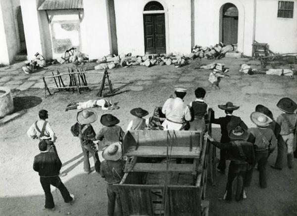 Scena del film "Un dollaro tra i denti" - Regia Luigi Vanzi, 1966 - Totale. Un gruppo di messicani, di spalle, guarda un gruppo di soldati morti sullo sfondo.