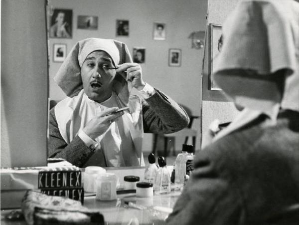 Scena del film "Domenica è sempre domenica" - Regia Camillo Mastrocinque, 1958 - Mezza figura di Alberto Sordi, riflesso allo specchio. L'attore si sta truccando e ha indosso, un telo in testa e un ampio bavaglio.