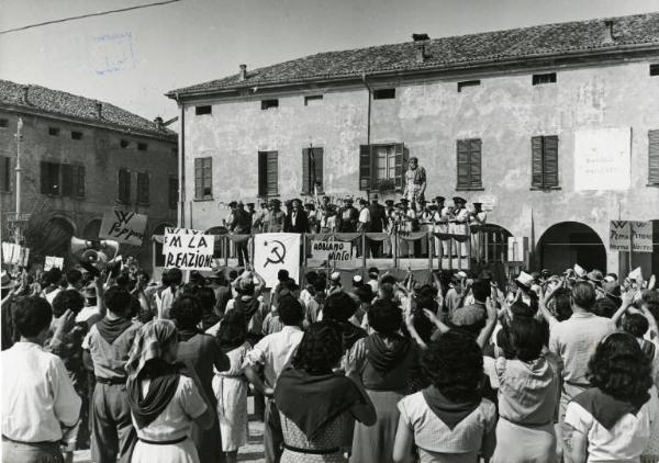 Scena del film "Don Camillo" - Regia Julien Duvivier, 1952 - Totale. Sullo sfondo, in una piazza sopra un palco di comizio Gino Cervi, la banda musicale e altre persone. In primo piano la folla applaude.