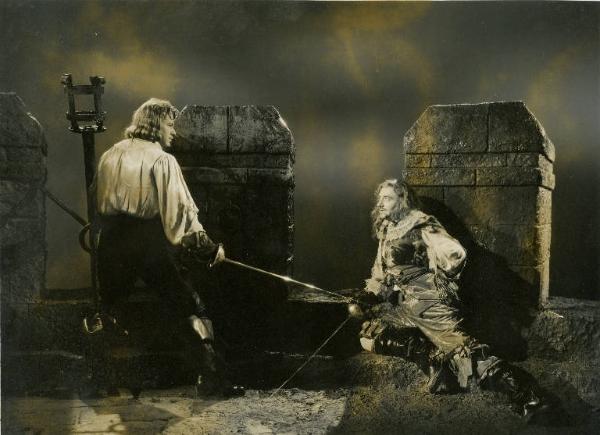 Scena del film "Don Cesare di Bazan" - Regia Riccardo Freda, 1942 - Sulla cima di un castello Enrico Glori è seduto a terra con la schiena appoggiata a un merlo e la spada rivolta a terra. Di fronte a lui, in piedi, Gino Cervi gli punta la sua spada.