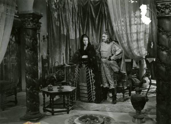 Scena del film "Don Cesare di Bazan" - Regia Riccardo Freda, 1942 - Totale. Enrico Glori tiene le mani sui fianchi e guarda Anneliese Uhlig al suo fianco.