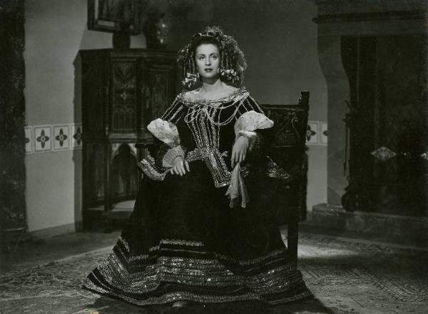 Scena del film "Don Cesare di Bazan" - Regia Riccardo Freda, 1942 - Figura intera di Anneliese Uhlig, seduta. L'attrice, tiene un fazzoletto a mezz'aria, tra due dita.