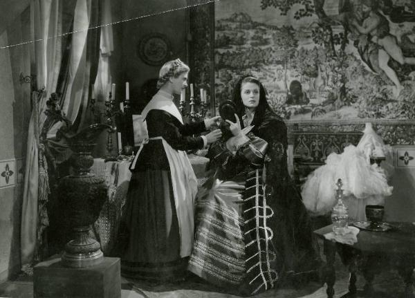 Scena del film "Don Cesare di Bazan" - Regia Riccardo Freda, 1942 - Figura intera di Anneliese Uhlig, in piedi, mentre tiene uno specchietto davanti al viso. Una domestica le sistema il velo.