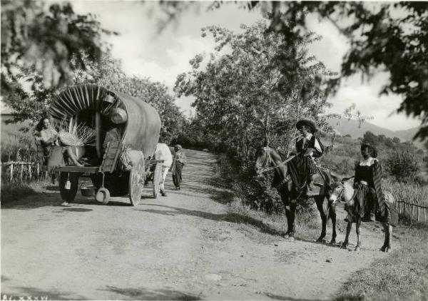 Scena del film "Don Giovanni" - Regia Dino Falconi, 1942 - Sul retro di un carro coperto, Elli Parvo intreccia una cesta di vimini. A destra, sul bordo della strada, Adriano Rimoldi in sella a un cavallo e Paolo Stoppa a un asino.