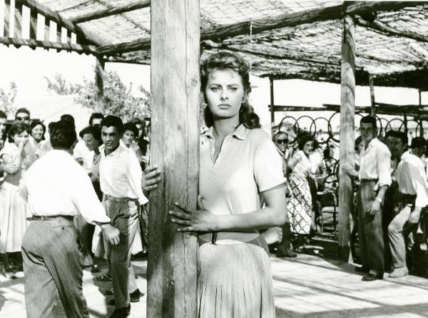 Scena del film "La donna del fiume" - Regia Mario Soldati, 1955 - Piano americano di Sophia Loren. L'attrice è appoggiata al palo di un gazebo. Sullo sfondo attori non identificati.