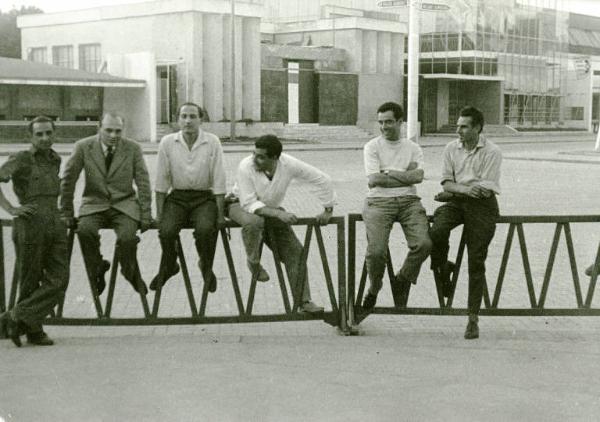 Sul set del film "La donna del giorno" - Regia Francesco Maselli, 1957 - Milano, Fiera del 1956. Sei uomini seduti su una ringhiera. Dal secondo a sinistra, Paul Ronald, Alvaro Lanzone, Armando Nannuzzi e Marcello Gatti.