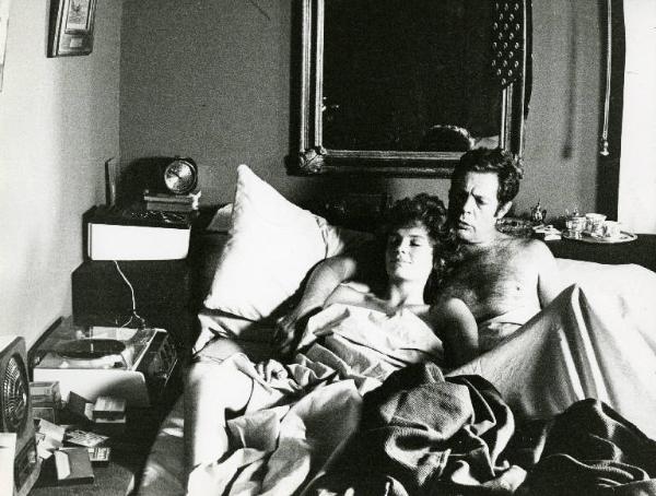 Scena del film "La donna della domenica" - Regia Luigi Comencini, 1975 - Marcello Mastroianni e Jacqueline Bisset a letto. L'attrice appoggia il capo sulla spalla di lui e sorride beata.