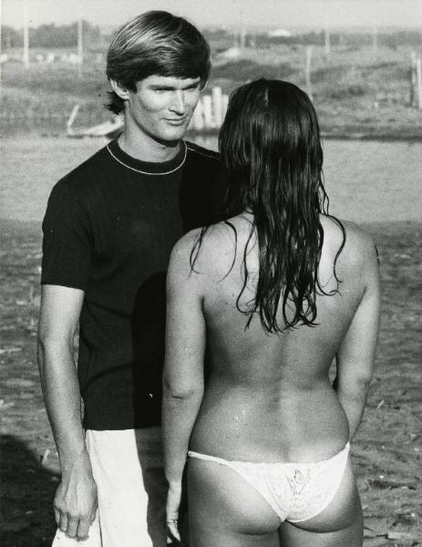 Scena del film "Una donna... e una donna" - Regia Luigi Petrini, 1969 - In spiaggia. Piano americano di Bernard De Vries e Susanna Levi. L'attore guarda negli occhi l'attrice, di spalle, che indossa solo il pezzo sotto del costume da bagno.