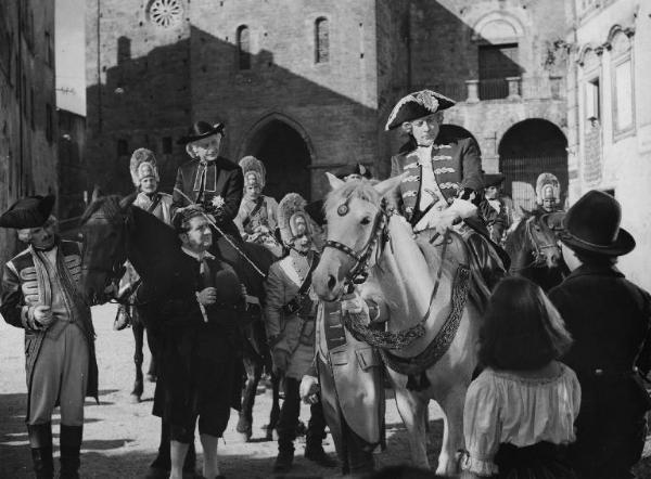 Scena del film "Donne e briganti" - Regia Mario Soldati, 1950 - In una piazza, Giuseppe Porelli ed Enrico Viarisio a cavallo. In mezzo, Nando Bruno in piedi con il cappello in mano. Dietro e intorno a loro soldati e popolani.