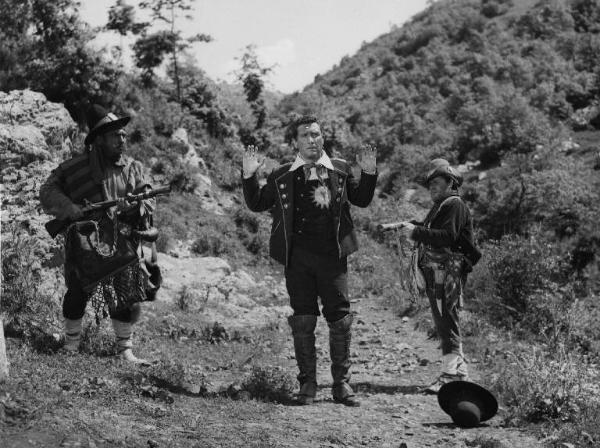 Scena del film "Donne e briganti" - Regia Mario Soldati, 1950 - Figura intera frontale di Paolo Stoppa con le mani in alto. L'attore è tenuto sotto tiro da due attori non identificati.