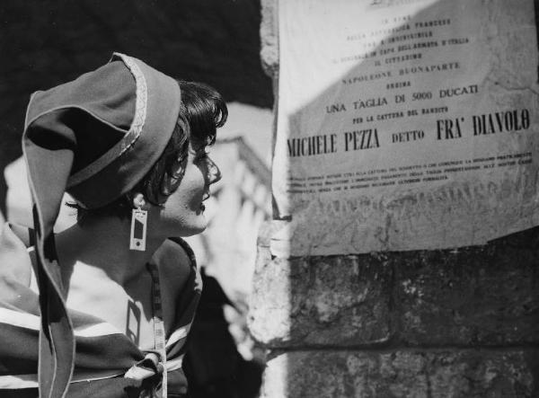 Scena del film "Donne e briganti" - Regia Mario Soldati, 1950 - Primo piano di profilo di Jacqueline Pierreux. L'attrice legge un affisso murale che riporta la taglia su "Fra' Diavolo".