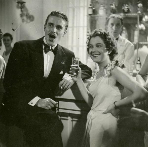 Scena del film "Dopo divorzieremo" - Regia Nunzio Malasomma, 1940 - Mezza figura di Lilia Silvi e Amedeo Nazzari, appoggiati a un bancone da bar in abiti da sposi.