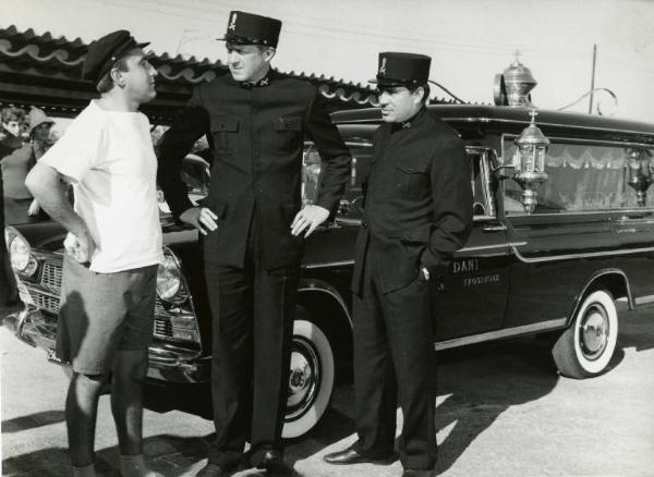 Scena del film "Una domenica d'estate" - Regia Giulio Petroni, 1962 - Ugo Tognazzi, a destra, Raimondo Vianello, al centro e, un attore non identificato, in piedi, davanti a un carro funebre.