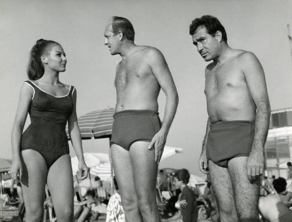 Scena del film "Una domenica d'estate" - Regia Giulio Petroni, 1962 - In spiaggia, piano americano di Dominique Boschero, Raimondo Vianello e Ugo Tognazzi in costume da bagno.